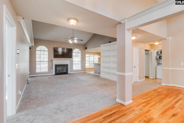 unfurnished living room with carpet floors, lofted ceiling, a ceiling fan, and a glass covered fireplace