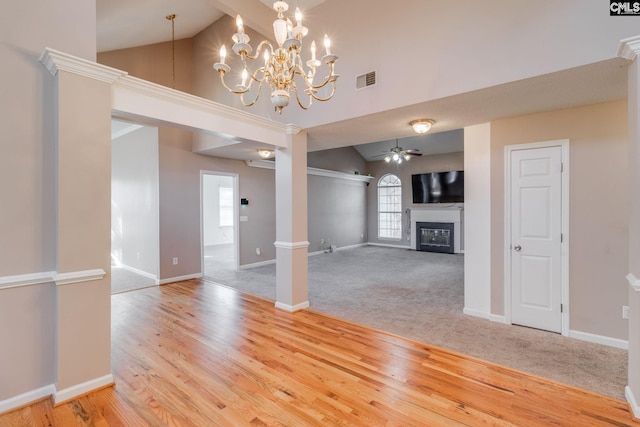 unfurnished living room featuring ceiling fan with notable chandelier, a glass covered fireplace, visible vents, and light wood-style floors