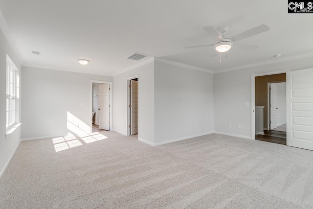 carpeted spare room with a ceiling fan, visible vents, crown molding, and baseboards