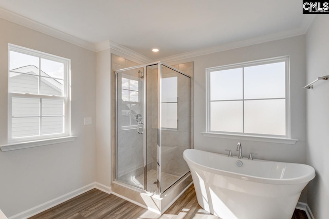 bathroom with baseboards, ornamental molding, wood finished floors, a freestanding bath, and a shower stall