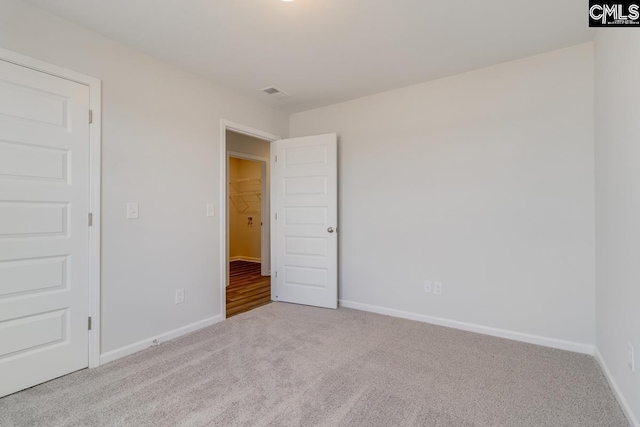 carpeted spare room featuring visible vents and baseboards