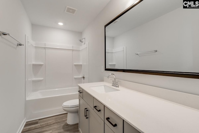 bathroom featuring visible vents, bathing tub / shower combination, toilet, wood finished floors, and vanity