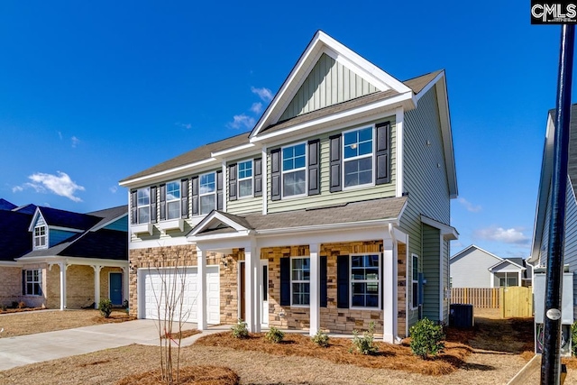 view of front of home featuring a porch, fence, stone siding, concrete driveway, and board and batten siding