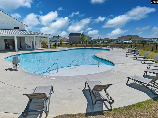 pool with a residential view, a patio area, and fence