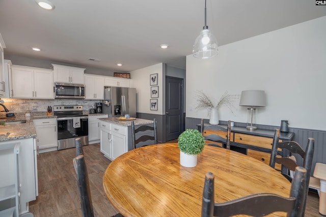 dining room with dark wood-style floors, recessed lighting, and a wainscoted wall