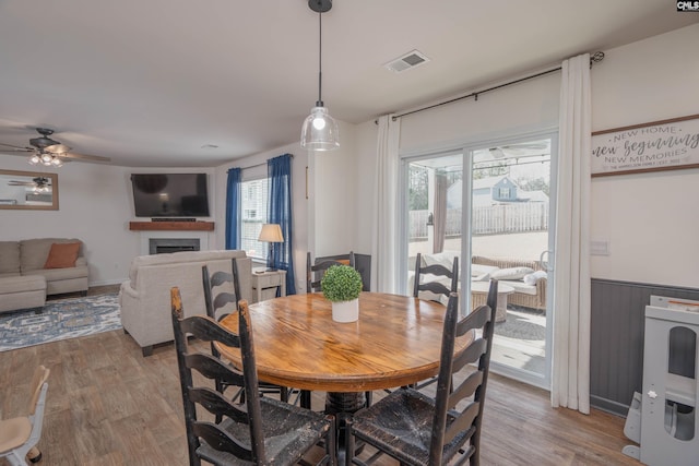 dining room featuring a wainscoted wall, a fireplace, visible vents, and light wood-style floors