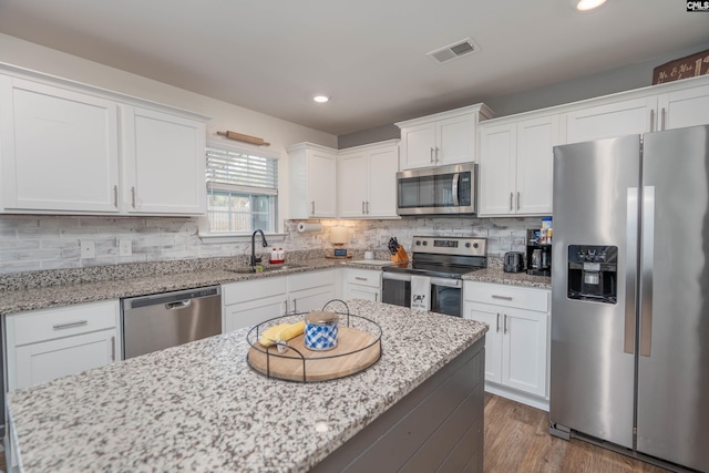 kitchen with a sink, visible vents, white cabinetry, appliances with stainless steel finishes, and tasteful backsplash