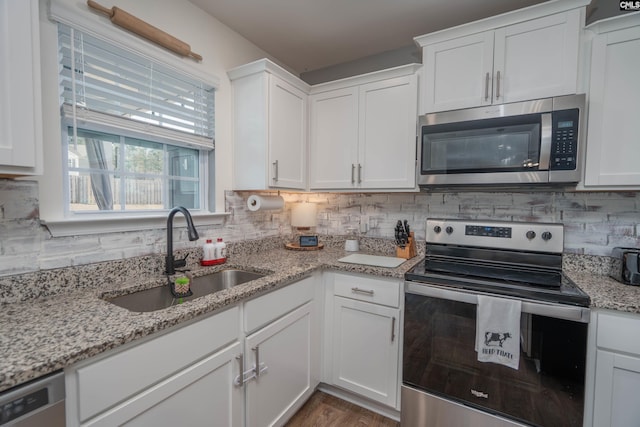 kitchen with tasteful backsplash, white cabinetry, stainless steel appliances, and a sink