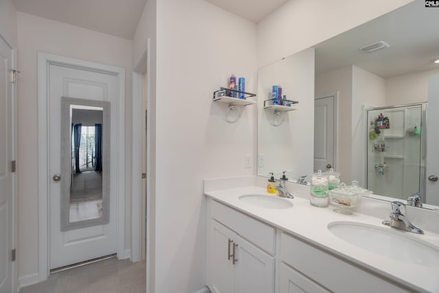 bathroom featuring a stall shower, visible vents, a sink, and double vanity