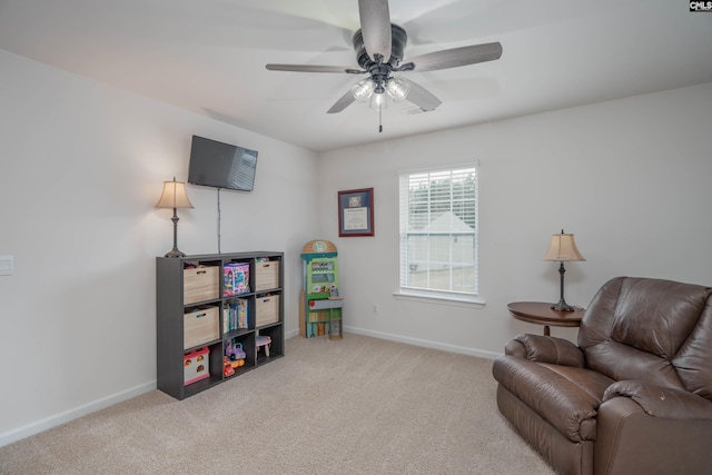 sitting room with carpet floors, baseboards, and a ceiling fan