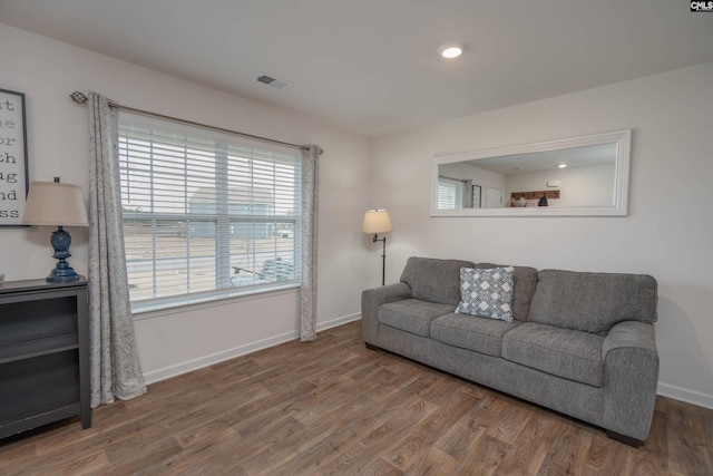 living area featuring baseboards, visible vents, and wood finished floors