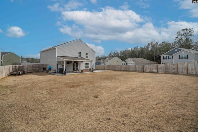 rear view of property with a fenced backyard, a lawn, and a patio