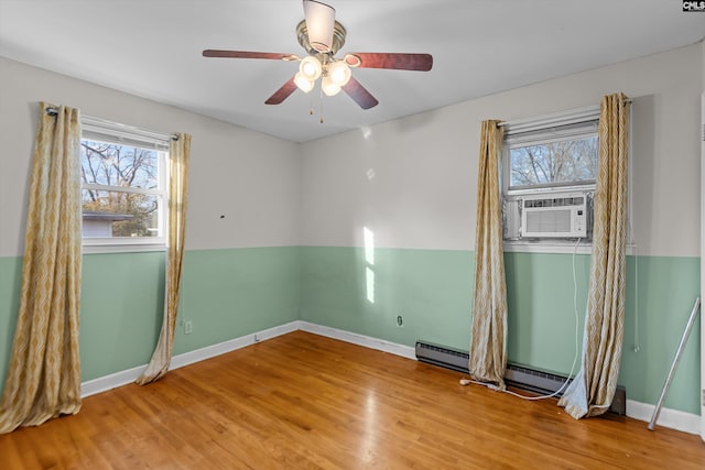 spare room with cooling unit, plenty of natural light, baseboards, and wood finished floors