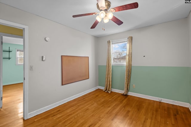 unfurnished room featuring a ceiling fan, baseboards, and wood finished floors