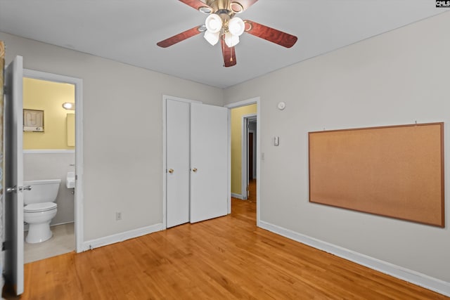 unfurnished bedroom with ensuite bath, baseboards, ceiling fan, and wood finished floors