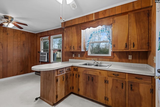 kitchen with wood walls, light countertops, a sink, and a peninsula