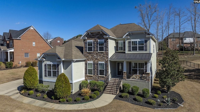 view of front of home featuring metal roof, stone siding, a porch, and a standing seam roof