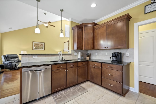 kitchen featuring a peninsula, a sink, open floor plan, stainless steel dishwasher, and dark stone countertops