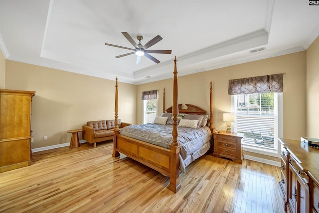 bedroom with a raised ceiling, visible vents, and multiple windows