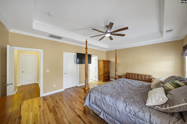 bedroom with wood finished floors, a raised ceiling, and visible vents