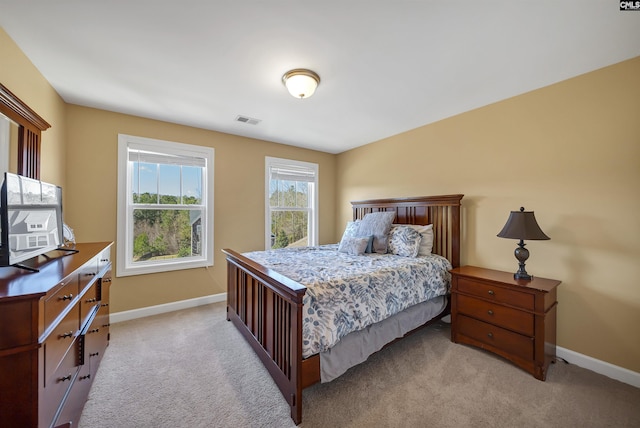 bedroom featuring visible vents, light carpet, and baseboards