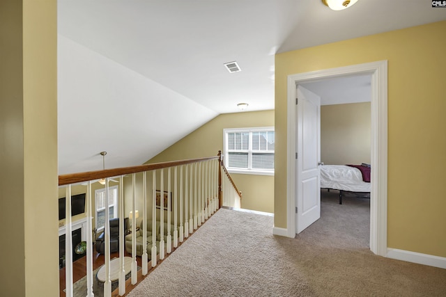 corridor with lofted ceiling, carpet floors, baseboards, and visible vents