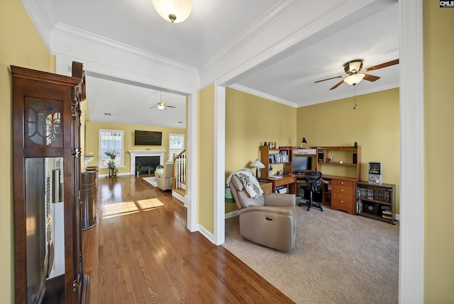 office with baseboards, a fireplace, wood finished floors, and crown molding