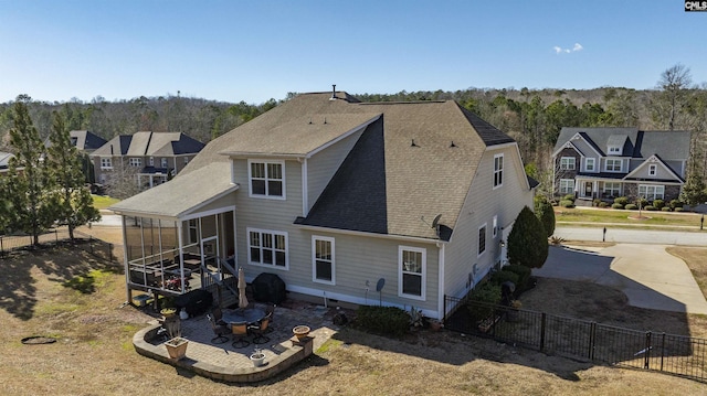 back of property with a patio, a shingled roof, fence, and a sunroom