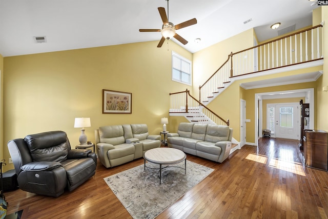 living area featuring visible vents, stairway, a towering ceiling, and hardwood / wood-style flooring