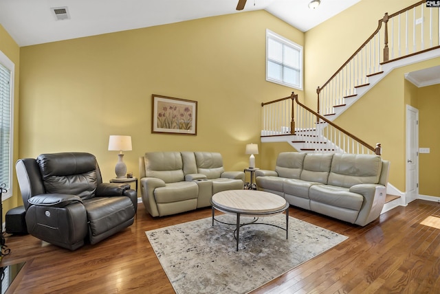 living room featuring high vaulted ceiling, wood-type flooring, stairs, and visible vents