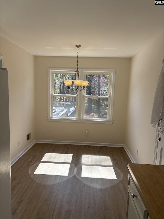 unfurnished dining area featuring dark wood-type flooring, baseboards, visible vents, and a wealth of natural light