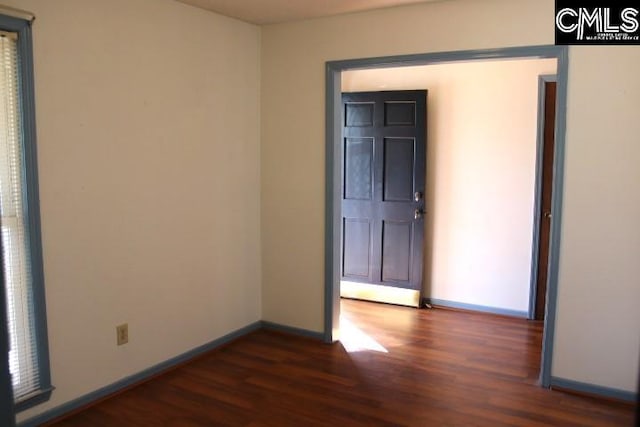 empty room featuring dark wood-style floors and baseboards