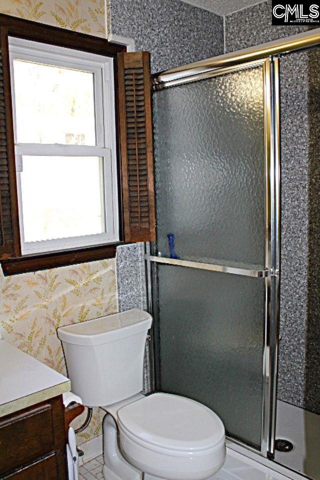 bathroom featuring toilet, wallpapered walls, vanity, and a stall shower