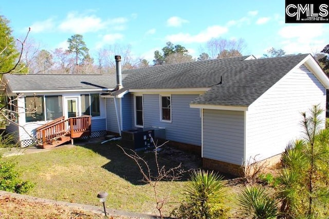 back of property with a shingled roof and a lawn