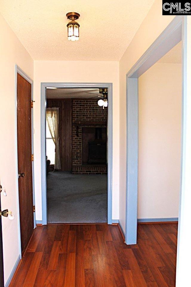 corridor featuring a textured ceiling, baseboards, and wood finished floors