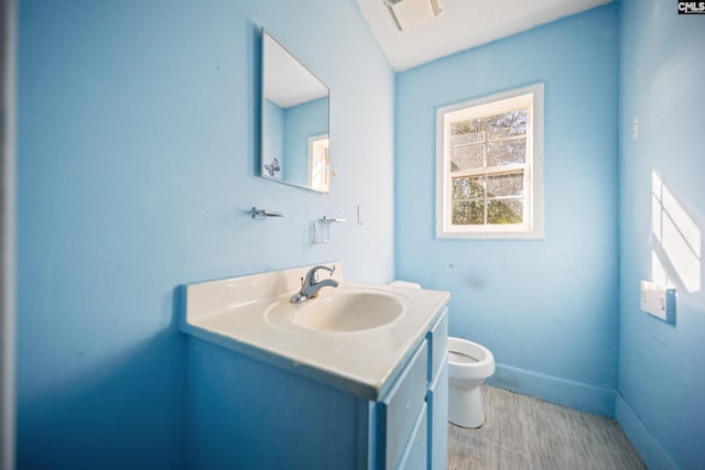 half bathroom featuring baseboards, visible vents, vanity, and toilet