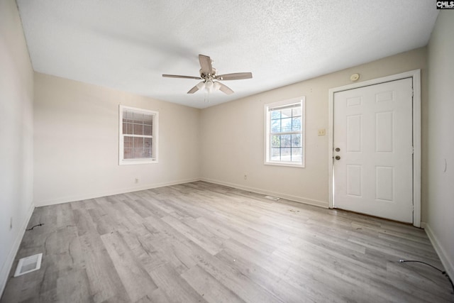 interior space with visible vents, ceiling fan, a textured ceiling, wood finished floors, and baseboards