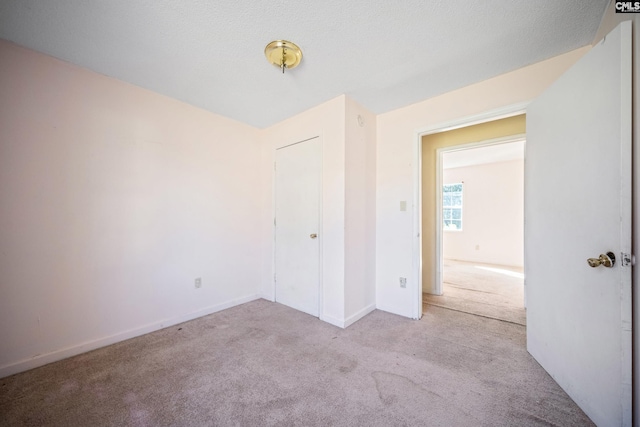 unfurnished bedroom with carpet flooring, a textured ceiling, and baseboards