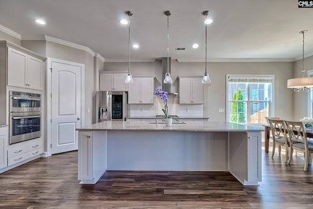 kitchen with a center island with sink, decorative backsplash, dark wood finished floors, light stone counters, and stainless steel appliances