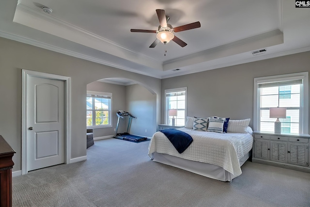 carpeted bedroom with crown molding, a tray ceiling, visible vents, and baseboards