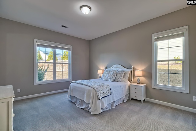 bedroom with carpet floors, visible vents, baseboards, and multiple windows