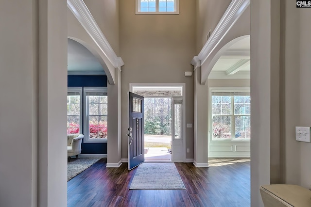 entrance foyer with arched walkways, dark wood-style flooring, baseboards, and a high ceiling