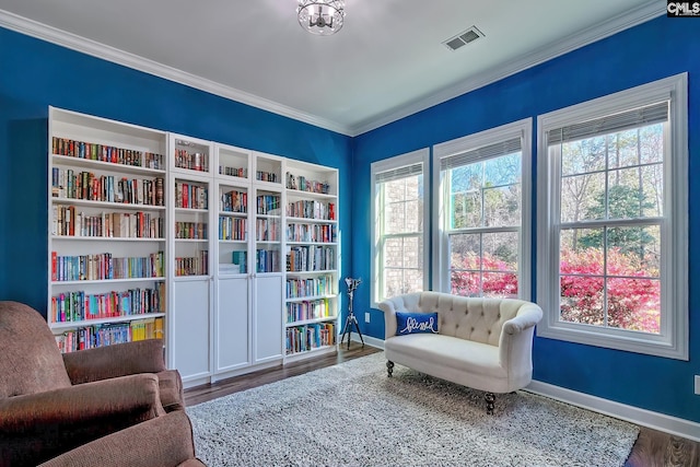 living area featuring ornamental molding, visible vents, baseboards, and wood finished floors