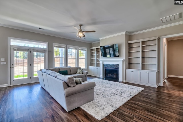 living area with dark wood finished floors, visible vents, ornamental molding, a high end fireplace, and ceiling fan