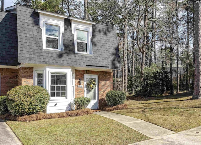 view of front of house with a shingled roof, mansard roof, and brick siding