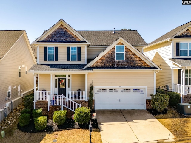 craftsman-style house with roof with shingles, central air condition unit, covered porch, an attached garage, and driveway