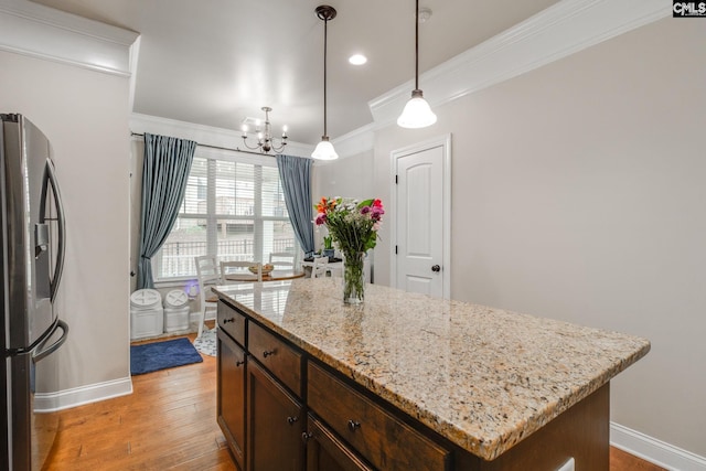 kitchen with dark brown cabinetry, light wood-style floors, stainless steel fridge with ice dispenser, ornamental molding, and a center island