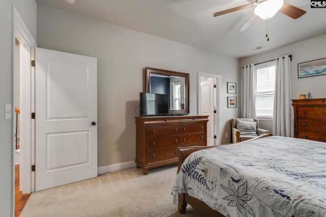 bedroom with light colored carpet, ceiling fan, visible vents, and baseboards