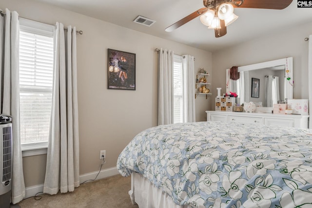 bedroom featuring light colored carpet, visible vents, baseboards, and multiple windows