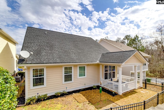 back of house with a shingled roof and fence